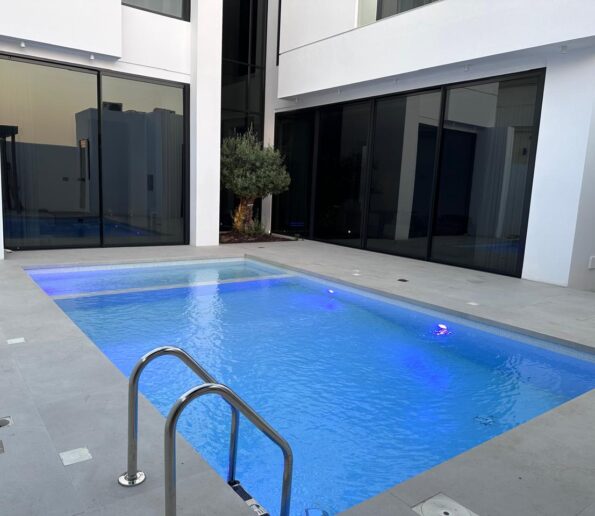 Modern swimming pool with sleek design and stainless steel handrails