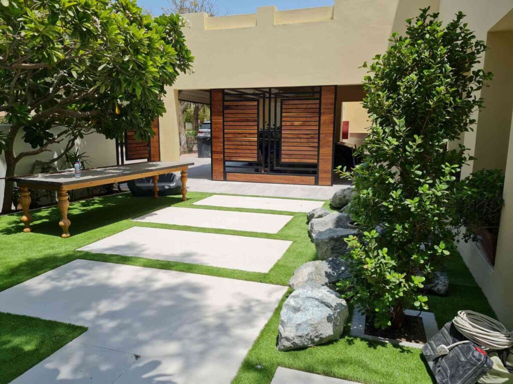 Beautifully landscaped garden with pathway and a pool surrounded by lush greenery in a Dubai residence, showcasing a well-maintained outdoor space.